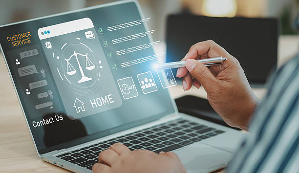Businessman points a pen at a laptop screen showing an online legal advice website, featuring customer service AI chatbot interface and justice scale graphics in a bright office background.